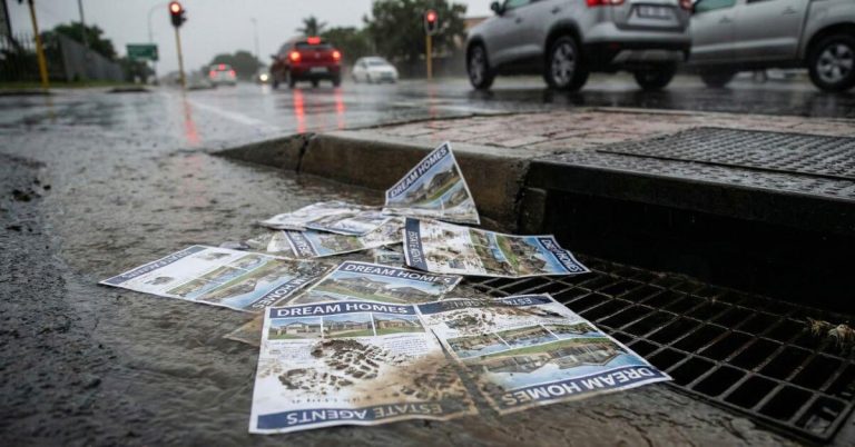 Mentoring Intern Estate Agents. Wet real estate flyers being washed down a storm drain at a traffic light.