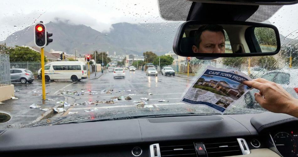 Why Traditional Estate Agents Are Failing. Driver ignoring a real estate flyer being pushed against the car window at a robot.