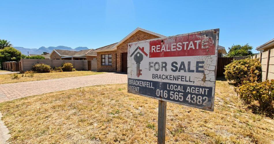 How to Overcome Call Reluctance in Real Estate. Faded real estate for sale sign on lawn.